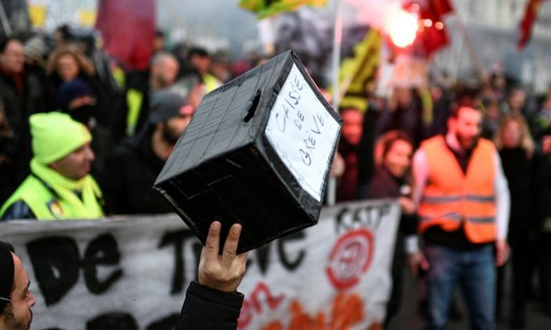 Multiple funds have been launched to help compensate striking workers. The picture shows a marcher holding up a contribution box