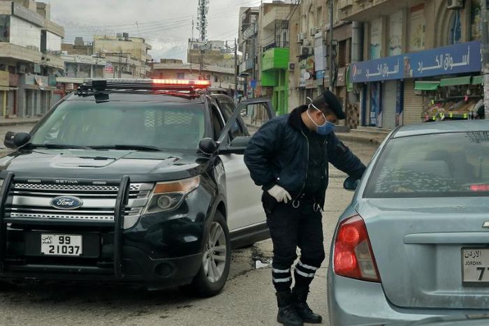 A policeman speaks to a driver at a checkpoint in the Jordanian capital Amman during a nationwide curfew imposed to control the spread of the novel coronavirus