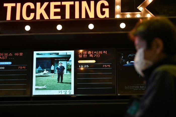 A man walks past a screen showing a poster of Bong Joon-ho's film 'Parasite' at a cinema in Seoul on the day the movie won the Oscar for best picture