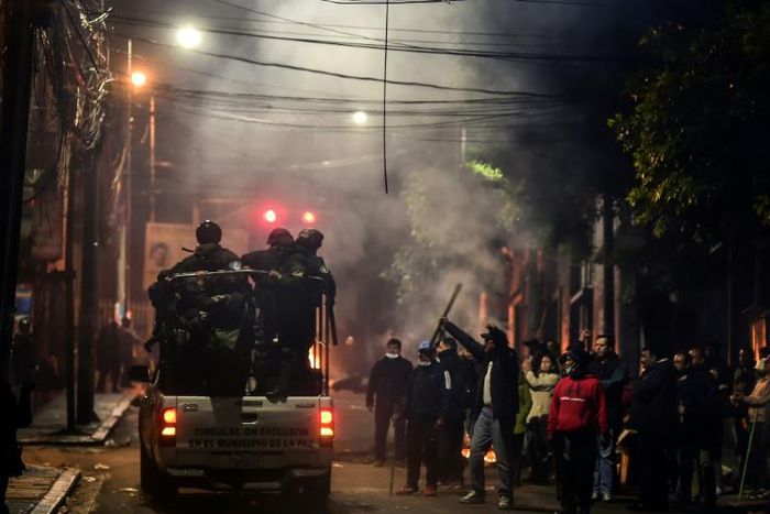 People gesture at policemen in La Paz, Bolivia on November 11, 2019 after president Evo Morales announced his resignation