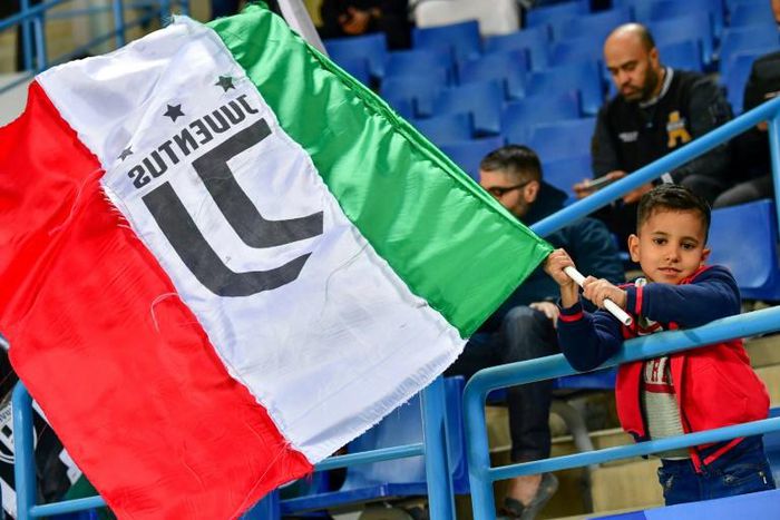 A young Juventus supporter waves the Italian flag.