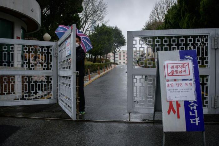 A security guard stands at the entrance to an apartment complex reserved for young, poor women, which has seen nearly a third of its 142 residents test positive for the coronavirus, in Daegu
