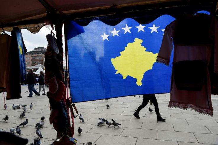 A pedestrian walks behind the Kosovo flag ahead of last year's 10th-anniversary celebrations in Pristina of Kosovo's declaration of independence