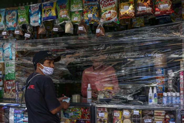 A man shops at a store covered with plastic as a precautionary measure against the spread of the new coronavirus, COVID-19, in Caracas, on March 17, 2020President Nicolas Maduro asked the International Monetary Fund on Tuesday for a $5 billion loan to ...