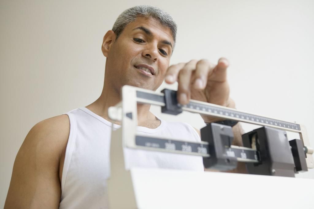 Middle aged man weighing himself