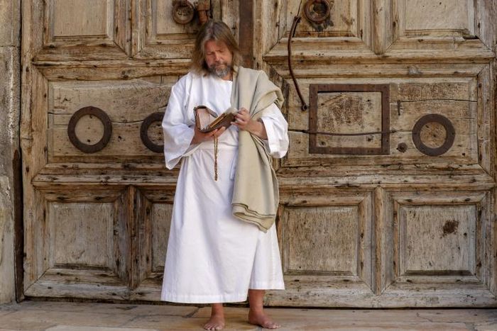 A worshipper prays in front of the closed door of the Holy Sepulchre Church in Jerusalem's Old City amid movement restrictions due to the coronavirus pandemic