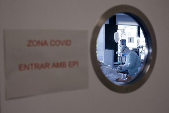 A healthcare worker in a protective suit attends to a COVID-19 coronavirus patient at a hospital in Barcelona