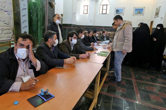 Organisers wear masks as they oversee voting in Iran's Friday parliamentary election days after the coronavirus outbreak first emerged