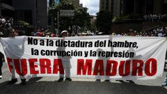 Supporters of Venezuelan opposition leader Juan Guaido hold a banner reading "Maduro Out" as they protest against President Nicolas Maduro in Caracas