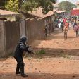 An anti-riot policeman faces young demonstrators in Conakry -- one of many protests that have unfurled over planned changes to the constitution