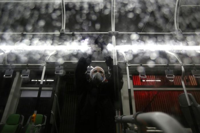 A city council worker in protective clothing disinfects a bus in Tehran as part of government efforts to control a novel coronavirus outbreak that has now killed 19 people