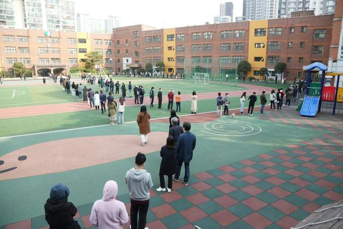 South Koreans wait in line to cast their ballots at a polling station in Seoul on April 15