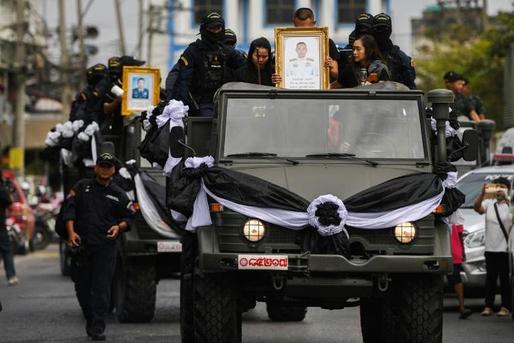 Relatives and family hold pictures as the coffins of SWAT team members Trakool Tha-arsa (front) and Petcharat Kamjadpai, killed in the mass shooting, are transported Nakhon Ratchasima