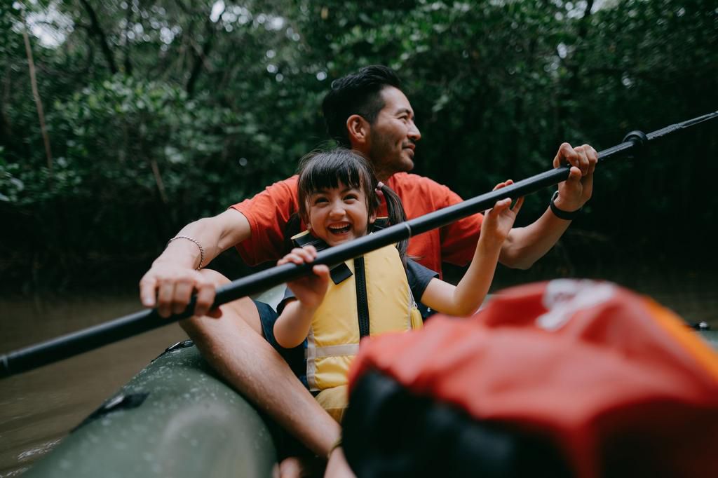 Father and child paddling kayak together in mangrove swamp, Japan