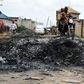 A motorcycle taxi in the district of Ojodu drives past the remains of a fire set to ward off gangs of robbers