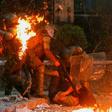 A demonstrator is held while a petrol bomb hits riot police during a protest against the government in Santiago on Friday