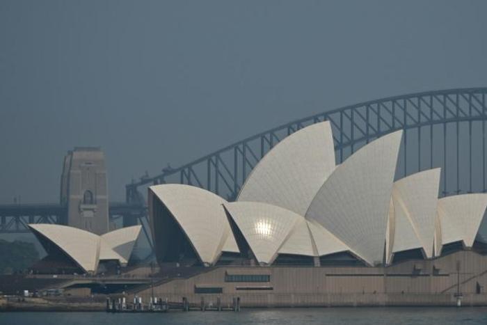 The Sydney Opera House and Harbour Bridge are seen through a smokey haze blanketing the city