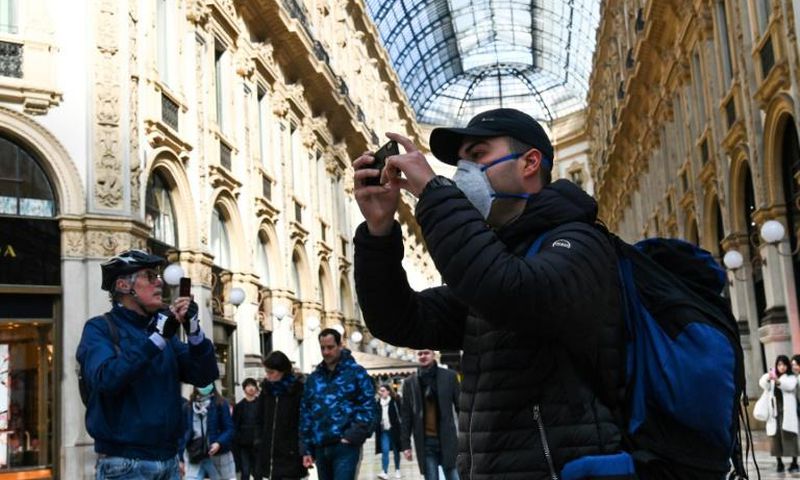 A man wearing a protective facemask takes pictures at the Gallery Vittorio Emanuele II in Milan on Monday