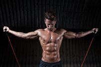 Macho Man Exercising With Resistance Bands Against Corrugated Iron