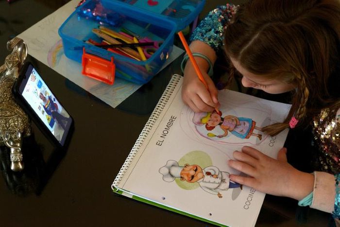 A six-year-old Spanish girl studies while watching a video of her teacher in Sevilla on April 14, 2020 amid a national lockdown to stop the spread of the COVID-19 coronavirus