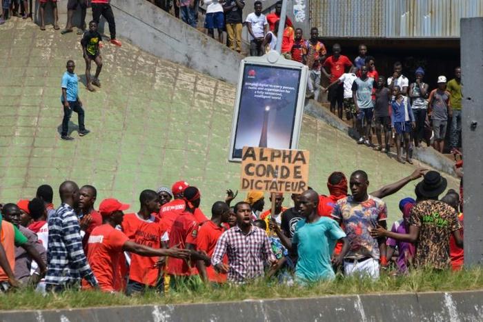 A man holds a sign reading "Alpha Conde dictator" during Thursday's protests