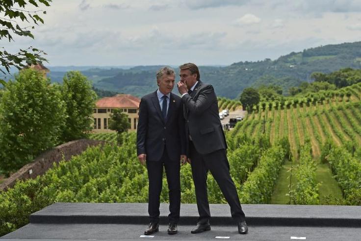 Brasil's President Jair Bolsonaro (R) talks with Argentina's Presidnt Mauricio Macri at a meeting of the  four-nation trade bloc Mercosur in Bento Goncalves, Brasil
