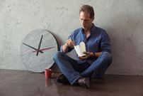 middle aged man eating noodles while sitting on the floor