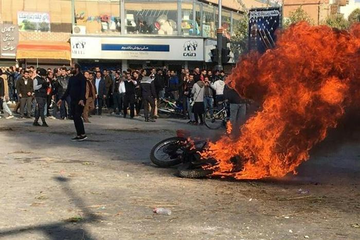 Iranian protesters gather around a burning motorcycle in the city of Isfahan during a demonstration last month against an increase in fuel prices