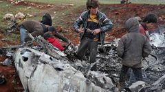 Syrians inspect the wreckage of a regime military helicopter after it was brought down over western Aleppo province
