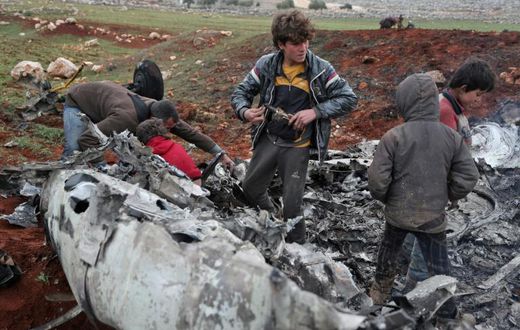 Syrians inspect the wreckage of a regime military helicopter after it was brought down over western Aleppo province