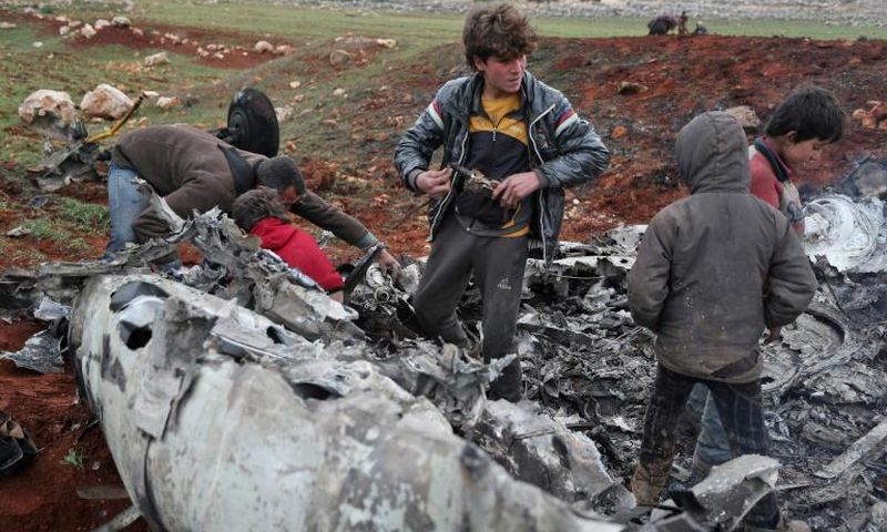 Syrians inspect the wreckage of a regime military helicopter after it was brought down over western Aleppo province