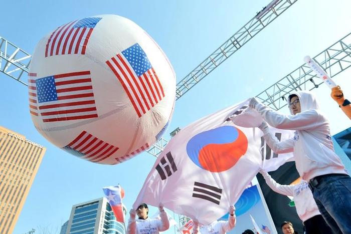 South Korean conservative activists roll a large balloon showing the US flags by a South Korean flag during a rally to support South Korea-US free trade agreement in Seoul in 2012