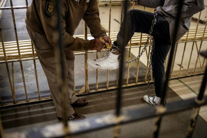 Confined: A guard locks ankle chains on a prisoner at Johannesburg's Sun City Prison