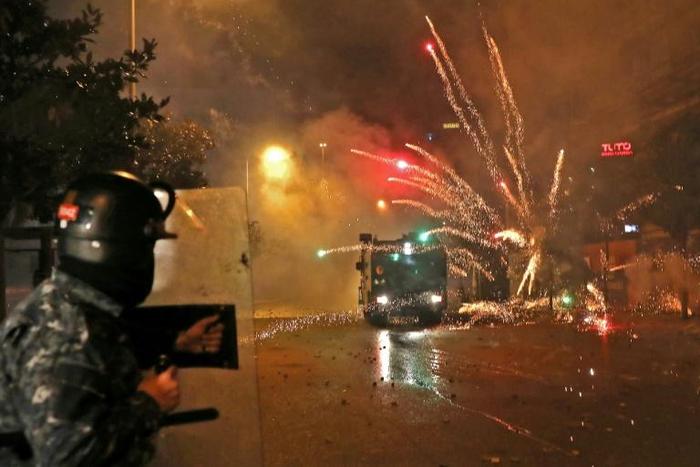 Supporters of Lebanon's two Shiite political parties throw fireworks towards anti-riot police trying to prevent them from attacking the main protest camp in central Beirut