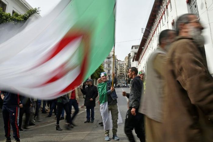 An Algerian protester waves the national flag during a weekly anti-government demonstration in the capital Algiers on March 13 before the rallies were suspended because of the novel coronavirus