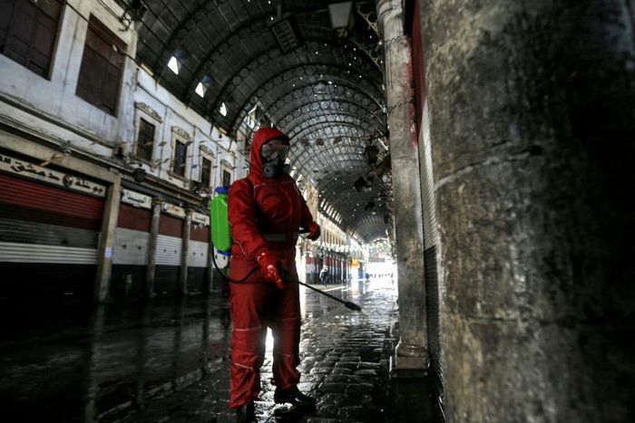 A Red Crescent member sprays disinfectant along an alley of the historic Hamidiya souk (market) in the old city of Syria's capital Damascus as part of efforts against the coronavirus pandemic