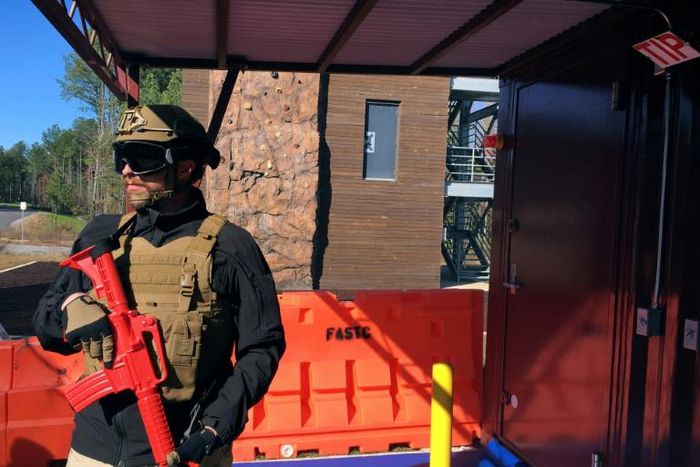 An armed officer stands outside of smoke-filled room during a media tour of a new training facility for US personnel overseas