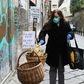 A woman puts food in a solidarity basket displayed with a note reading, "Who can put, who cannot take" in Naples, as Italy sees evidence it may have made it through the worst of the coronavirus pandemic