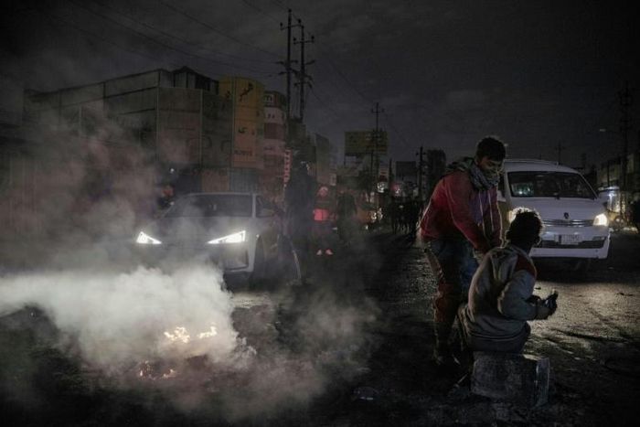 Iraqi youths block a street leading to Baghdad's al-Tayaran square on January 21