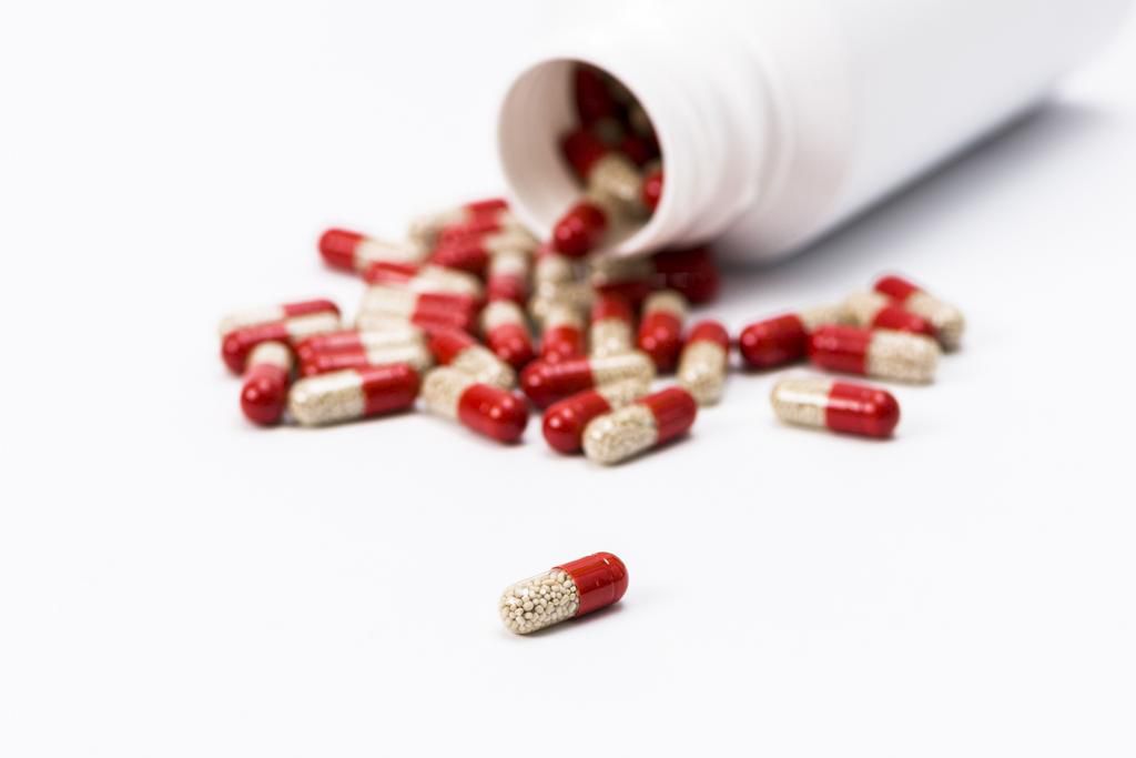 Many red and transparent medical capsules, filled with