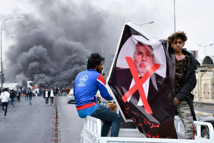 Iraqi demonstrators carry a poster of former premier-designate Mohammad Allawi covered with a red 'x' during an anti-government protest in Nasiriyah, on February 16