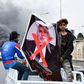 Iraqi demonstrators carry a poster of former premier-designate Mohammad Allawi covered with a red 'x' during an anti-government protest in Nasiriyah, on February 16