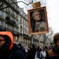 A protester holds a portrait of French President Emmanuel Macron painted as a royalty with a sign on top of it reading "14 May 2017 restoration of the monarchy"