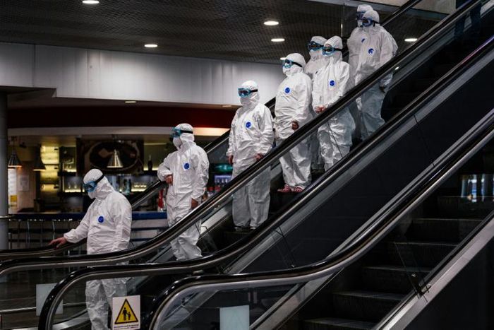 Medical staff wearing protective suits ride down an escalator at Moscow's Sheremetyevo airport