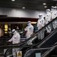 Medical staff wearing protective suits ride down an escalator at Moscow's Sheremetyevo airport