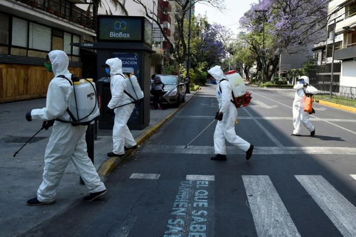 Cleaning workers wearing personal protective equipment disinfect a street in Mexico City amid the COVID-19 outbreak