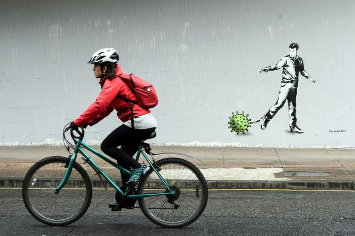 A cyclist passes  coronavirus-inspired graffiti in Glasgow on April 4, 2020, as life in Britain continues during the nationwide lockdown