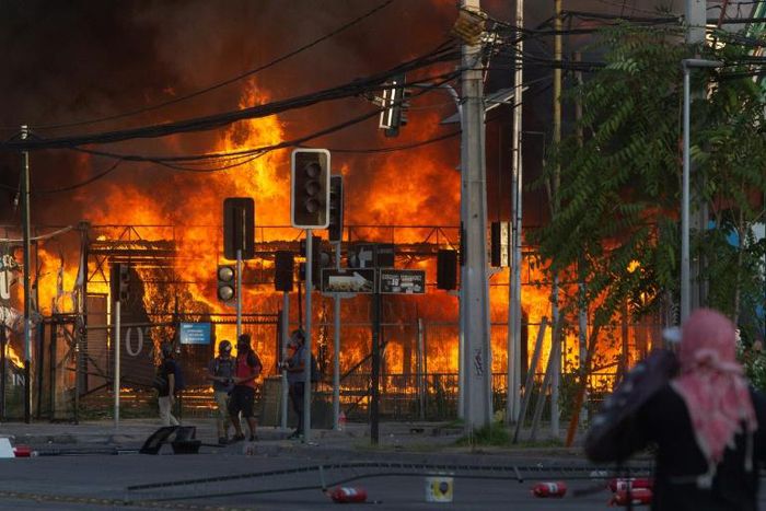 Demonstrators torch a shop in Santiago in protest at the death of a football fan who was hit by a police van