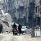 Syrian civilians walk thorugh the former rebel-held town of Harasta in Eastern Ghouta on March 30, 2018, a week after regime forces retook the town
