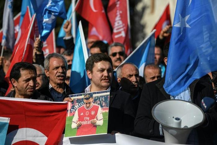 A supporter of China's Muslim Uighur minority holds a placard of Arsenal footballer Mesut Ozil during a demonstration in Istanbul